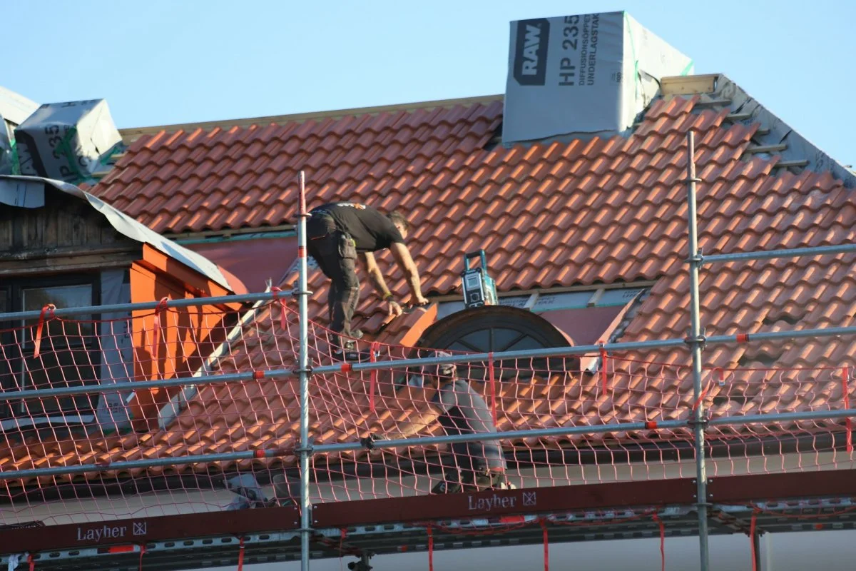 Roofing workers installing tile shingles on a residential roof in Tucson, Arizona