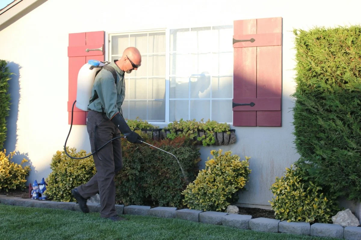 Pest control technician spraying treatment around a home in Tucson, Arizona