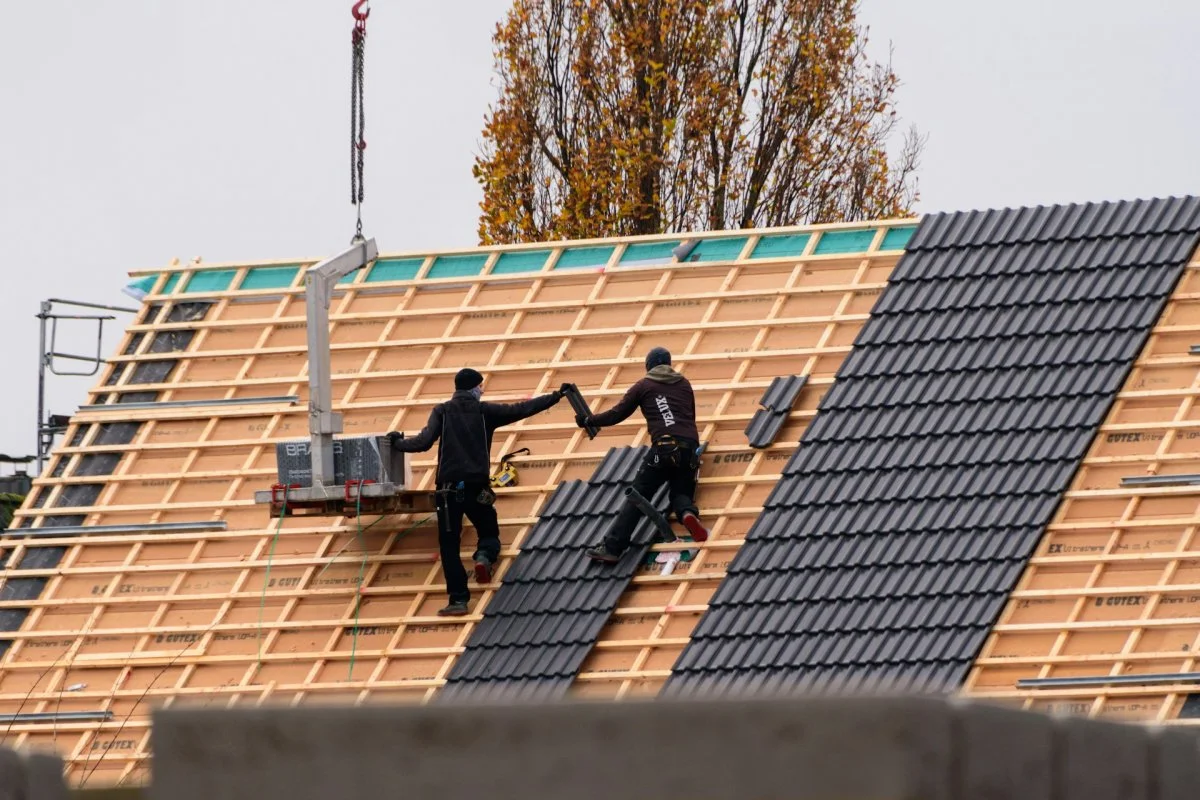 Two roofing workers installing a new roof on a residential home in Tucson, Arizona