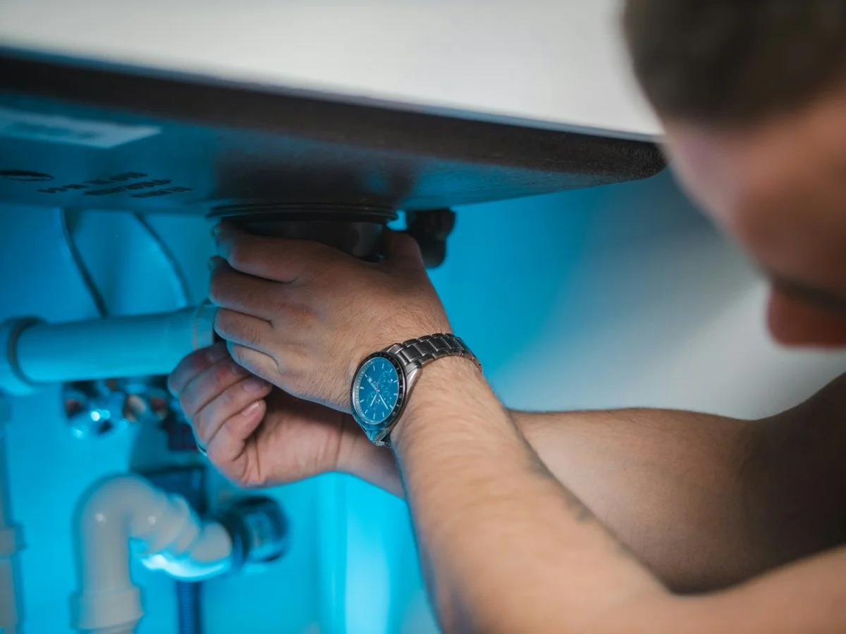 Plumber repairing pipes under a bathroom sink in Tucson, Arizona